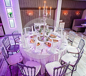 Wedding reception dinner. Round table served with flowers, shiny candles and appetizer food. Holiday banquet menu