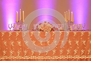 Wedding reception or fine dining table setup with embroidered organza tablecloth, crystal candle holders and a floral arrangement