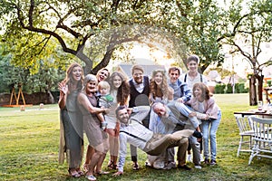 Bride, groom and guests posing for the photo at wedding reception outside in the backyard.