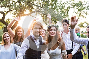 Bride, groom, guests posing for the photo at wedding reception outside in the backyard.