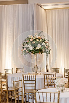 a wedding reception room decorated in gold and white furniture, candles, flowers and draper