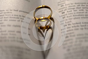 Wedding Ring on the bible with shadow of heart shape on the page