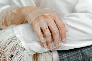 the wedding ring on the bride& x27;s finger. The groom hugs her from behind