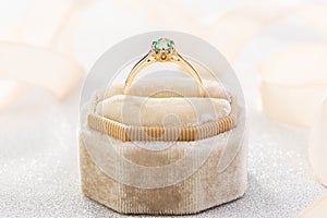 Wedding ring with emerald green gemstone in beige velvet jewelry box