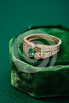 Wedding ring with emerald green gemstone on green velvet jewelry box