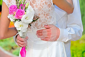 The wedding ring: groom hand embraces the waist of the bride. We