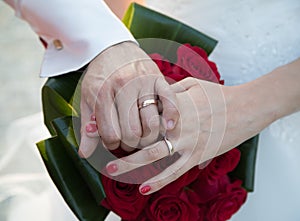 Wedding Ring Hands over red bouquet