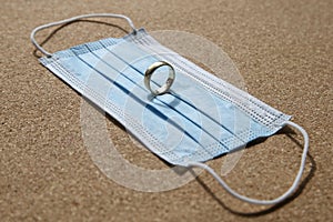 A wedding ring on a medical face mask. Divorce and marriage separation concept image.