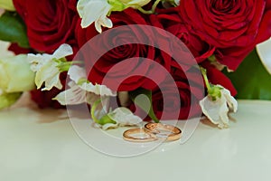 Wedding ring. Two gold vintage rings of bride and groom with diamonds and a bouquet of red roses and white flowers