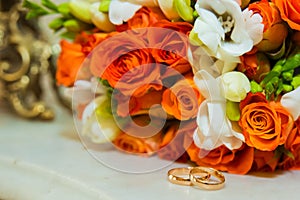 Wedding ring. Two gold vintage rings and a bride`s bouquet of orange roses and white flowers