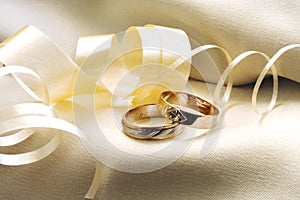 Los anillos de boda de cerca en el fondo blanco con la fiesta de la cinta.