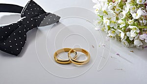 Wedding rings and accessories on white table elevated view