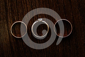 Wedding rings arranged on the brown wooden table.