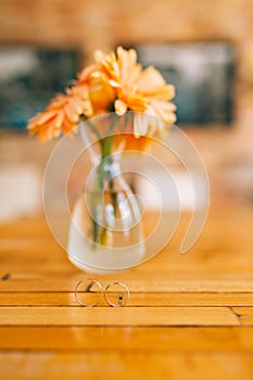 Wedding rings on a background of gerbera flower vases. Wedding j