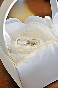 Wedding rings in a basket on white rose petals