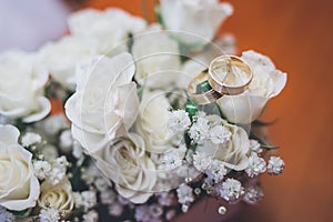 Wedding rings on beautiful white flowers bouquet. Copy space.