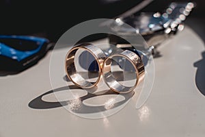 Wedding rings. Black leather shoes, watch, blue bow tie and cufflinks, on a white window sill.