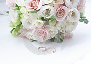 Wedding rings on a blue and white background next to a bouquet of flowers