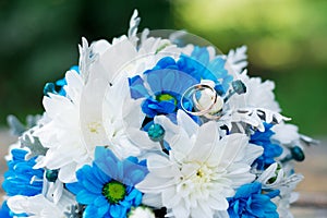 Wedding rings on a bouquet of blue and white flowers.