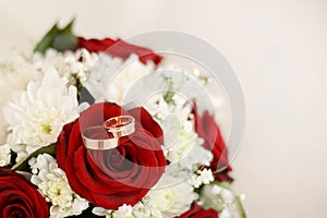 Wedding rings and bouquet of red and white flowers. light background with copy space