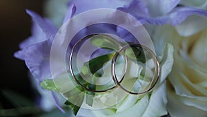 Wedding rings on a bouquet of white flowers close up. Wedding rings and bouquet of dark blue flower. Close up. Wedding