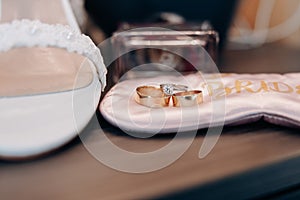 Wedding rings of the bride and groom close-up against the background of a bouquet of flowers and shoes
