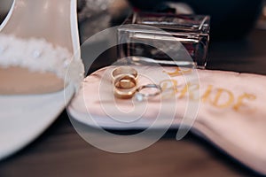 Wedding rings of the bride and groom close-up against the background of a bouquet of flowers and shoes