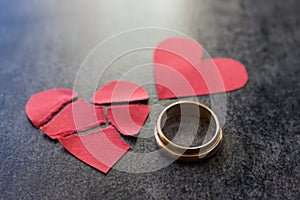 Wedding rings and broken red heart. Black background. The conce