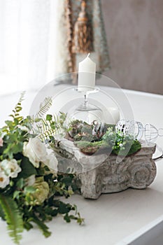 Wedding rings, candles, a glass, a decorative cage on chapiter, a bouquet of white roses photo