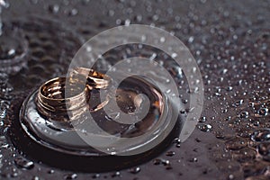 Wedding rings on a chrome plated surface. water drops with reflections of light. water splashes