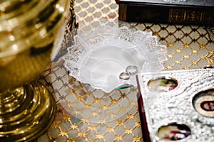 Wedding rings in church ready for marriage ceremony. close up. Bible, bowl in the church on table