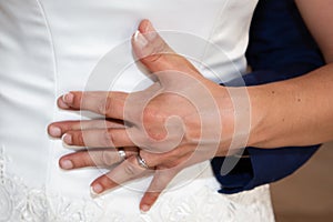 Wedding rings and couple hands fingers bride and groom in love over marriage dress background