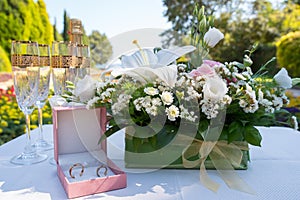Wedding rings and cups on a table with flowers