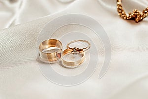 Wedding rings and an engagement ring with diamond on a silk background.