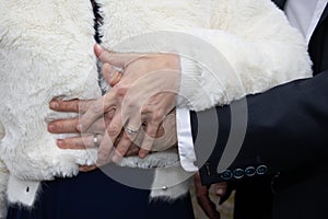 wedding rings fingers on couple marriage bride groom hands on white winter vest dress background