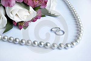 Wedding rings, flowers, beads on a white backgroun