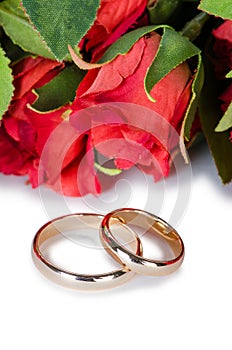 The wedding rings and flowers isolated on white background