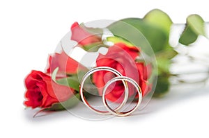 The wedding rings and flowers isolated on white background