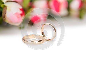 The wedding rings and flowers isolated on white background