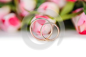 The wedding rings and flowers isolated on white background