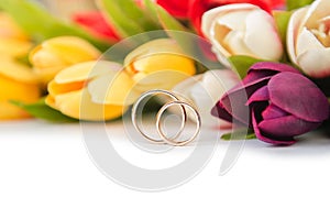 The wedding rings and flowers isolated on white background