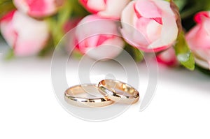 The wedding rings and flowers isolated on white background