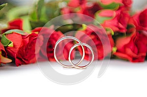 The wedding rings and flowers isolated on white background