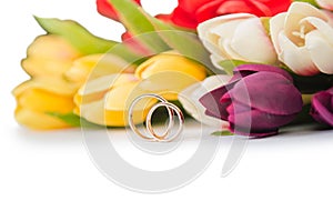 The wedding rings and flowers isolated on white background