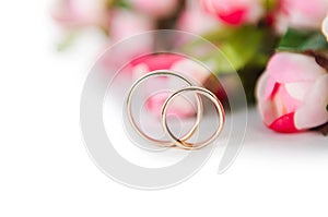 The wedding rings and flowers isolated on white background