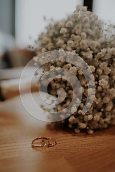 Wedding rings in focus on the table. The bouquet in the background is out of focus