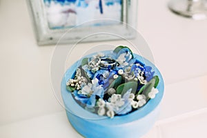 Wedding rings with a gems in a blue round box with blue flowers. Artwork. Soft focus