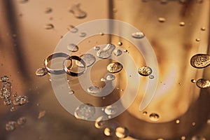 Wedding rings on glass with drops