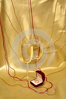Wedding rings and glasses with sparkling wine on a golden background