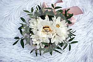 Wedding rings, gold and diamond on a white chrysanthemum, close-up. Two beautiful rings on the wedding bouquet, top view